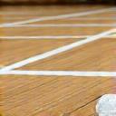 Badminton shuttlecock and racket on a wooden court floor.